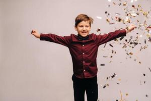 hermosa chico saltando para alegría y con papel picado en un gris antecedentes foto