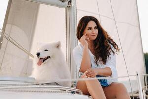a happy woman with a big white dog on a white yacht in the sea photo