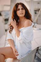 sexy woman in a white shirt enjoys the sunset on her private white yacht photo