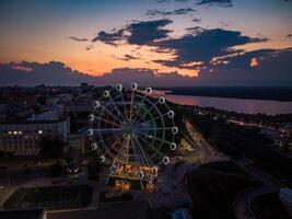 hermosa puesta de sol terminado el ciudad con un iluminado ferris rueda. foto