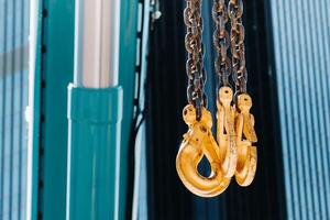 The hooks of the mobile crane near the glass of high buildings.Lots of hooks hanging from chains suspended from a crane photo