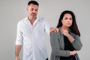 A woman beaten by her husband standing behind her and looking at her aggressively. Domestic violence photo