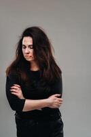 a battered woman in black clothes on an isolated gray background. Violence against women photo