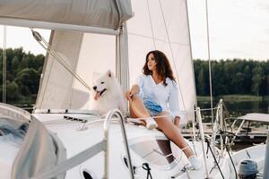 a happy woman with a big white dog on a white yacht in the sea photo