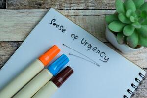 Concept of Sense of Urgency write on book isolated on Wooden Table. photo