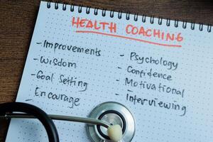 Concept of Health Coaching write on book with keywords isolated on Wooden Table. photo