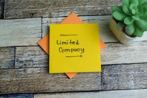 Concept of Limited Company write on sticky notes isolated on Wooden Table. photo