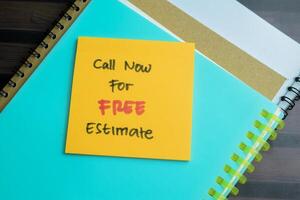 Concept of Call Now For Free Estimate write on sticky notes isolated on Wooden Table. photo