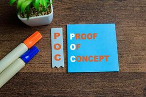 Concept of POC - Proof of Concept write on sticky notes isolated on Wooden Table. photo