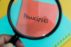 Concept of Principles write on sticky notes isolated on Wooden Table. photo