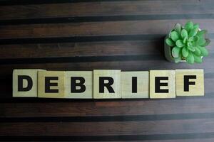 Concept of The wooden Cubes with the word Debrief on wooden background. photo
