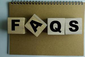 Concept of The wooden Cubes with the word Faqs on wooden background. photo