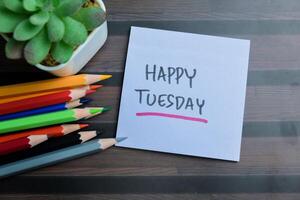 Concept of Happy Tuesday write on sticky notes isolated on Wooden Table. photo