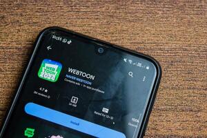 Webtoon 2024 application on Smartphone screen. Webtoon is a freeware web browser developed by Naver Webtoon. Bekasi, Indonesia, February 21, 2024 photo