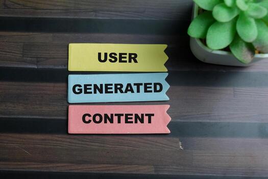 Concept of User Generated Content write on sticky notes isolated on Wooden Table. photo