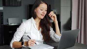 jovem mulher usando computador portátil dentro casa ambiente de trabalho, escrevendo notas, e-learning Educação conceito. Alto qualidade 4k cenas video