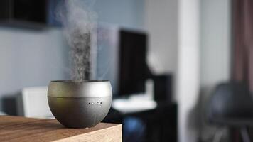 Grey aroma oil diffuser on light table at home, air freshener. High quality 4k footage video