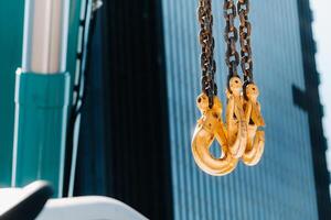 The hooks of the mobile crane near the glass of high buildings.Lots of hooks hanging from chains suspended from a crane photo