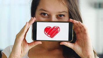 World Health Day concept. Young woman showing illustration of heart on her smartphone, illustrating the importance of cardiovascular health awareness on international health observation. video