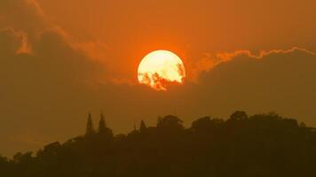 Time lapse of the sun setting over hills that are covered with clouds, in the style of smokey background. video