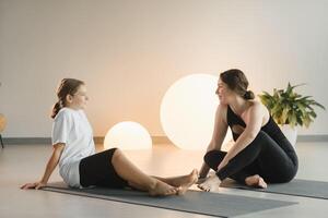 Mom and teenage daughter do gymnastics together in the fitness room. A woman and a girl train in the gym photo