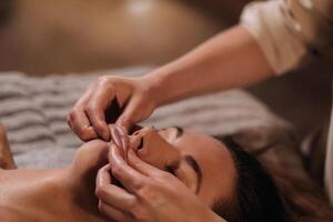 A cosmetologist girl does a facial and neck massage to a girl in the office for skin elasticity photo