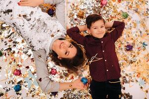 mother and son lie on the floor in confetti on a white background. A woman and a boy in confetti on a white background photo