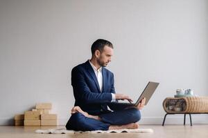 A man in a formal suit works sitting in a fitness room on a laptop photo