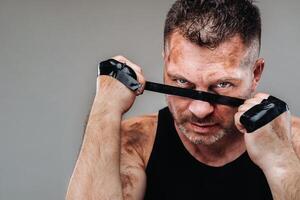 on a gray background stands a battered man in a black T shirt looking like a fighter and preparing for a fight photo