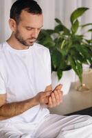 un hombre en blanco ropa de deporte es haciendo yoga con un aptitud habitación. el concepto de un sano estilo de vida foto