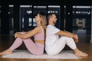 a woman and a man are engaged in pair gymnastics yoga in the gym photo