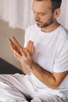 a man in white sportswear is doing yoga with a fitness room. the concept of a healthy lifestyle photo