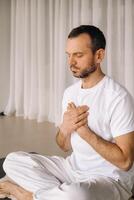 a man in white sportswear is doing yoga with a fitness room. the concept of a healthy lifestyle photo