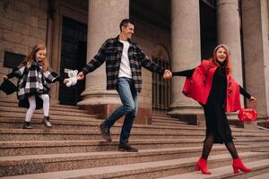 A stylish family of three strolls through the autumn city posing for a photographer . Dad, mom and daughter in the autumn city photo