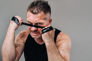 on a gray background stands a battered man in a black T shirt looking like a fighter and preparing for a fight photo