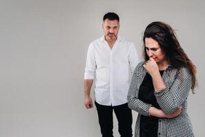 A woman beaten by a man stands on a gray background. Domestic violence photo