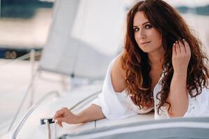 sexy woman in a white shirt enjoys the sunset on her private white yacht photo