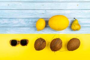 An assortment of yellow fruits and glasses lie on a blue wooden background and a yellow background photo