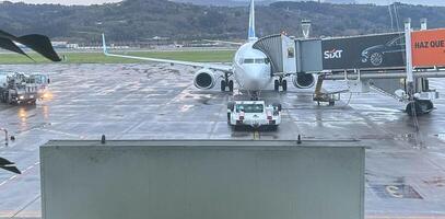 Bilbao, Vizcaya, Spain - February 26, 2024. Vueling Airbus 320 on tarmac refueling waiting at the finger for passengers flying to their holiday destination photo