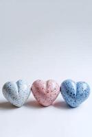 ai generado Tres cerámico corazones con moteado patrones en pastel azul, rosa, y oscuro azul, representando amor o san valentin día concepto, aislado en un blanco antecedentes foto