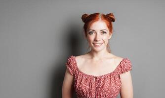 happy young woman with big toothy smile and red hair space buns photo