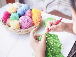 Close-up of woman hand knitting with green wool photo