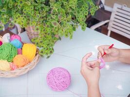 Close-up of woman hand knitting with pink wool photo