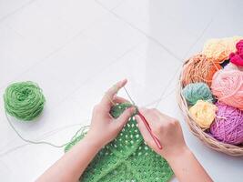 Close-up of woman hand knitting with green wool photo