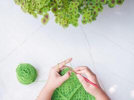 Close-up of woman hand knitting with green wool photo