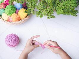 Close-up of woman hand knitting with pink wool photo