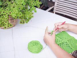 Close-up of woman hand knitting with green wool photo