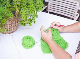 Close-up of woman hand knitting with green wool photo