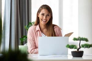 enfocado negocio mujer utilizando ordenador portátil a hogar, mirando a pantalla, charlando, leyendo o escritura correo electrónico, sentado en sofá, hembra estudiante haciendo tarea, trabajando en investigación proyecto en línea foto