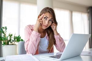 Exhausted businesswoman having a headache in modern office. Creative woman working at office desk feeling tired. Stressed casual business woman feeling head pain while overworking on desktop computer. photo